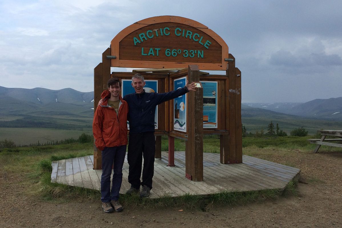 25C Peter And Jerome Ryan Pose In Front Of The Arctic Circle Sign Next To Dempster Highway In Yukon On Day Trip From Inuvik